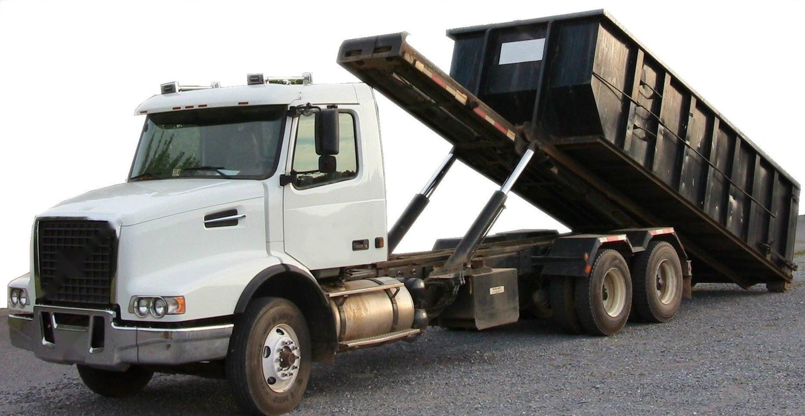 Roll-off truck tilting a steel dumpster container back to slide it onto the ground